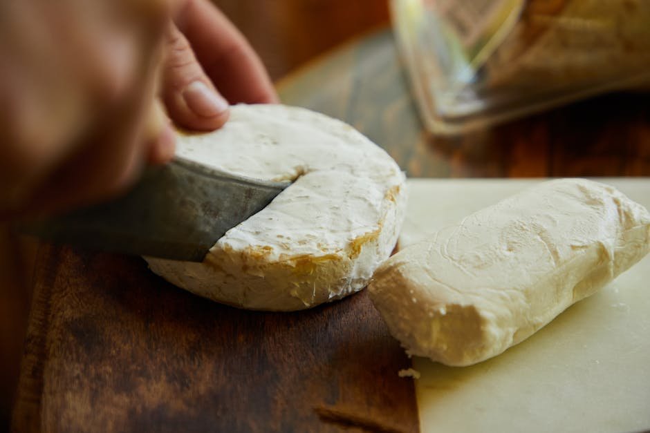 Gros plan sur la decoupe d une meule de fromage artisanal avec un couteau sur une planche en bois